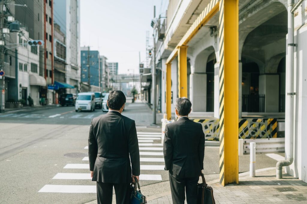 Two businessmen in suits waiting to cross a street in Japan